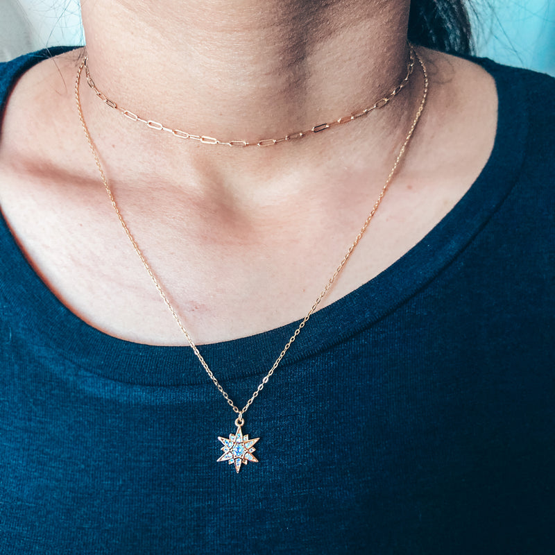 Model photo wearing gold layered necklaces with multi-point star charm