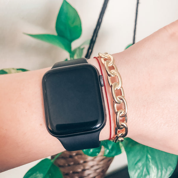 Model wearing chunky gold link chain cuff bracelet with stacked with Apple Watch 