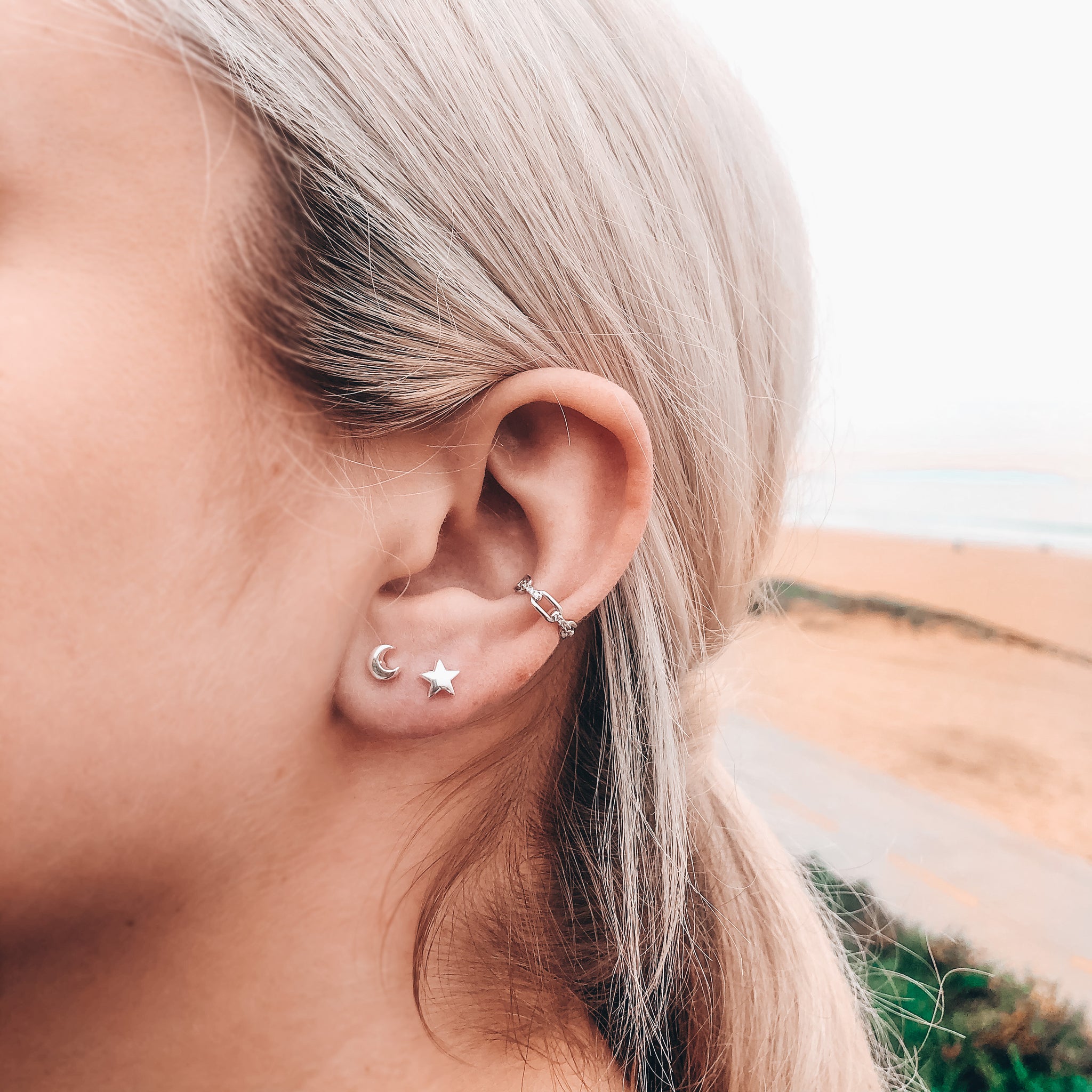 Model photo wearing Gold chain link ear cuff with CZ layered with star and moon studs