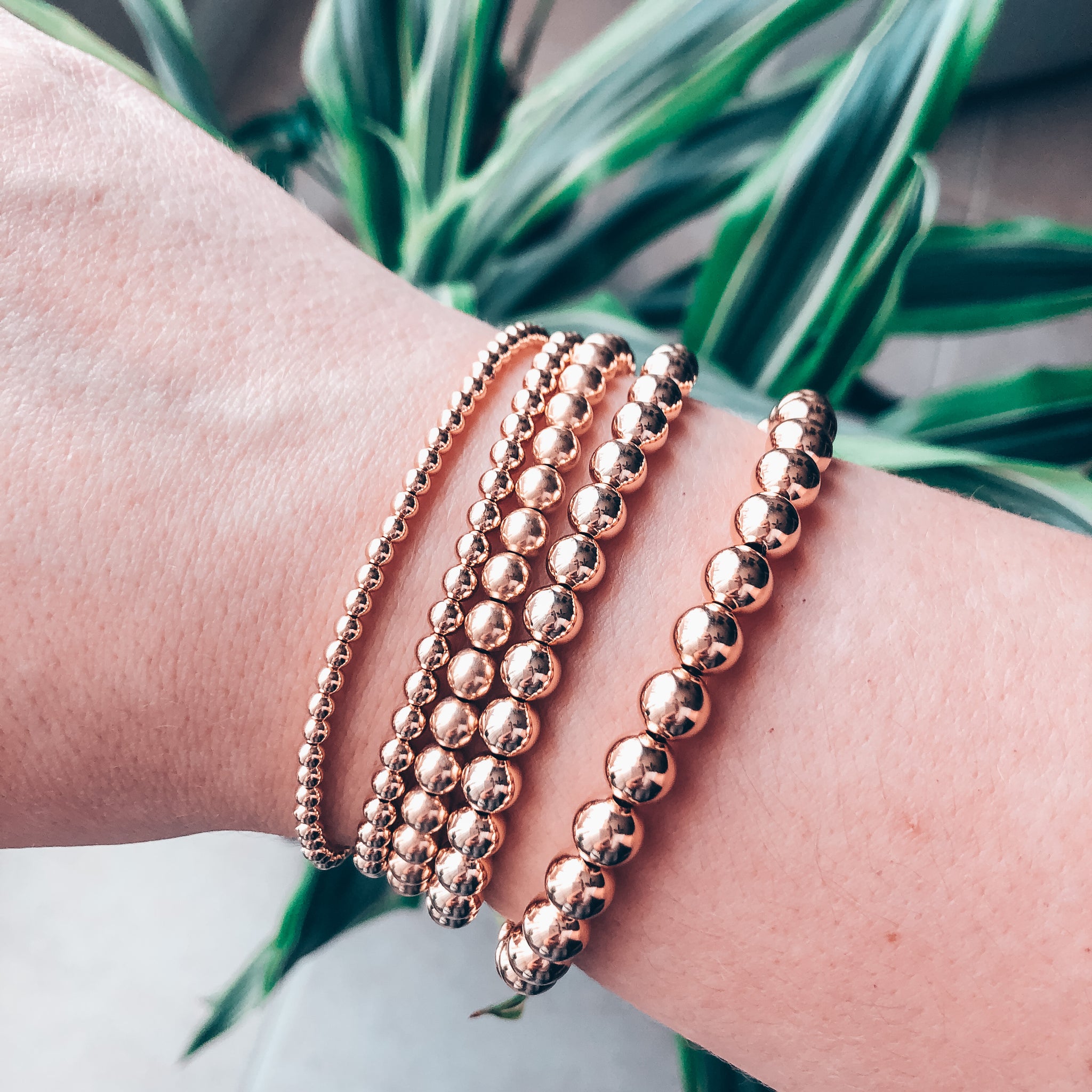 Model photo of wrist wearing stack of gold bracelets