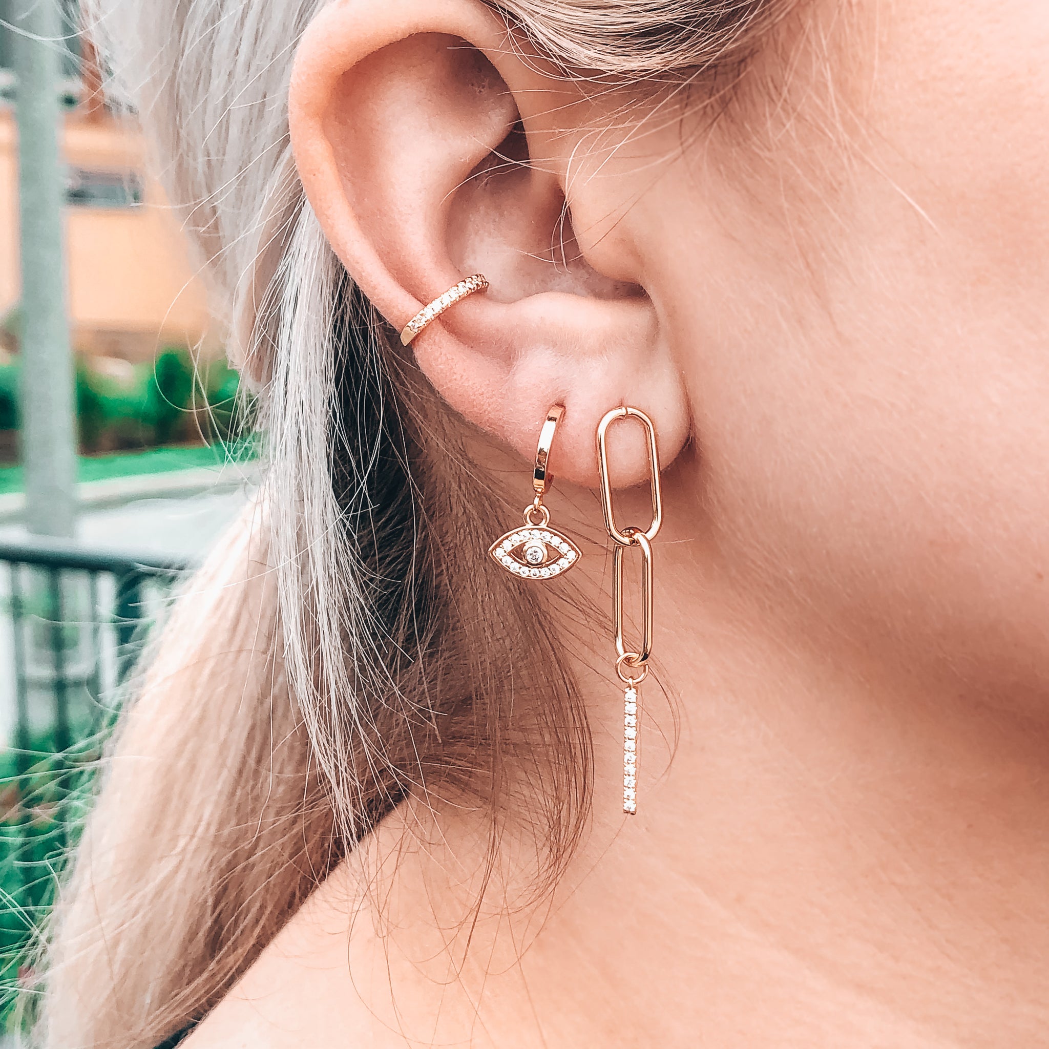 Model photo wearing layered earring look in gold including 14K Gold-Filled chain link post earrings with CZ drop