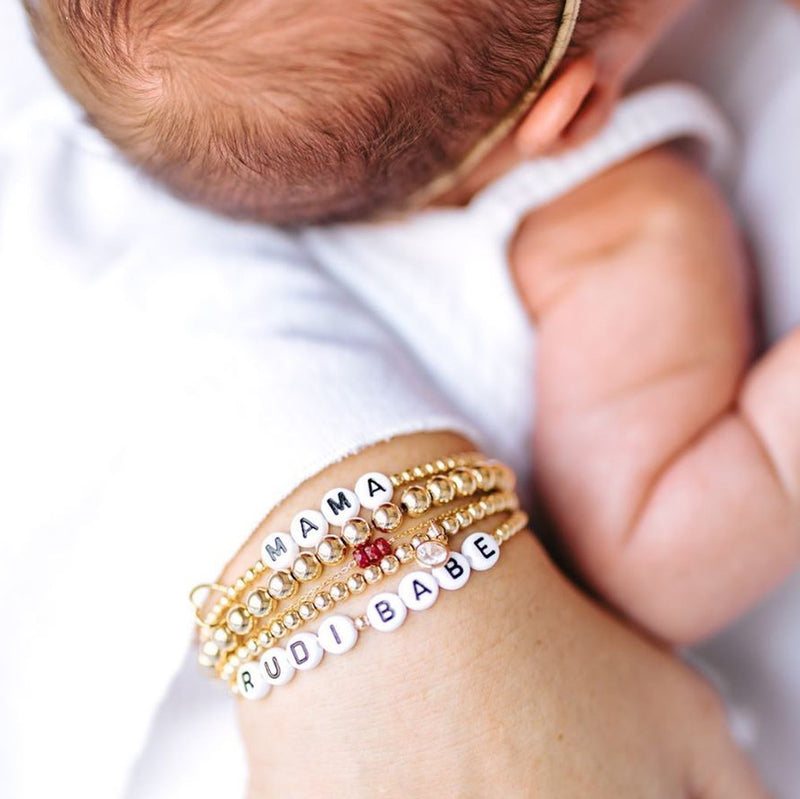 Model photo wearing 14k gold-filled 3mm beaded name bracelets customized matching set for mommy and baby with heart charms