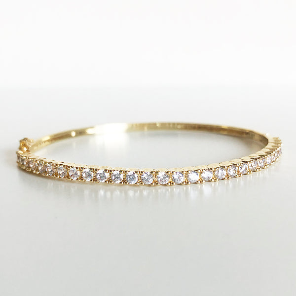 Gold and cubic zirconia latch-clasp bangle flat lay display