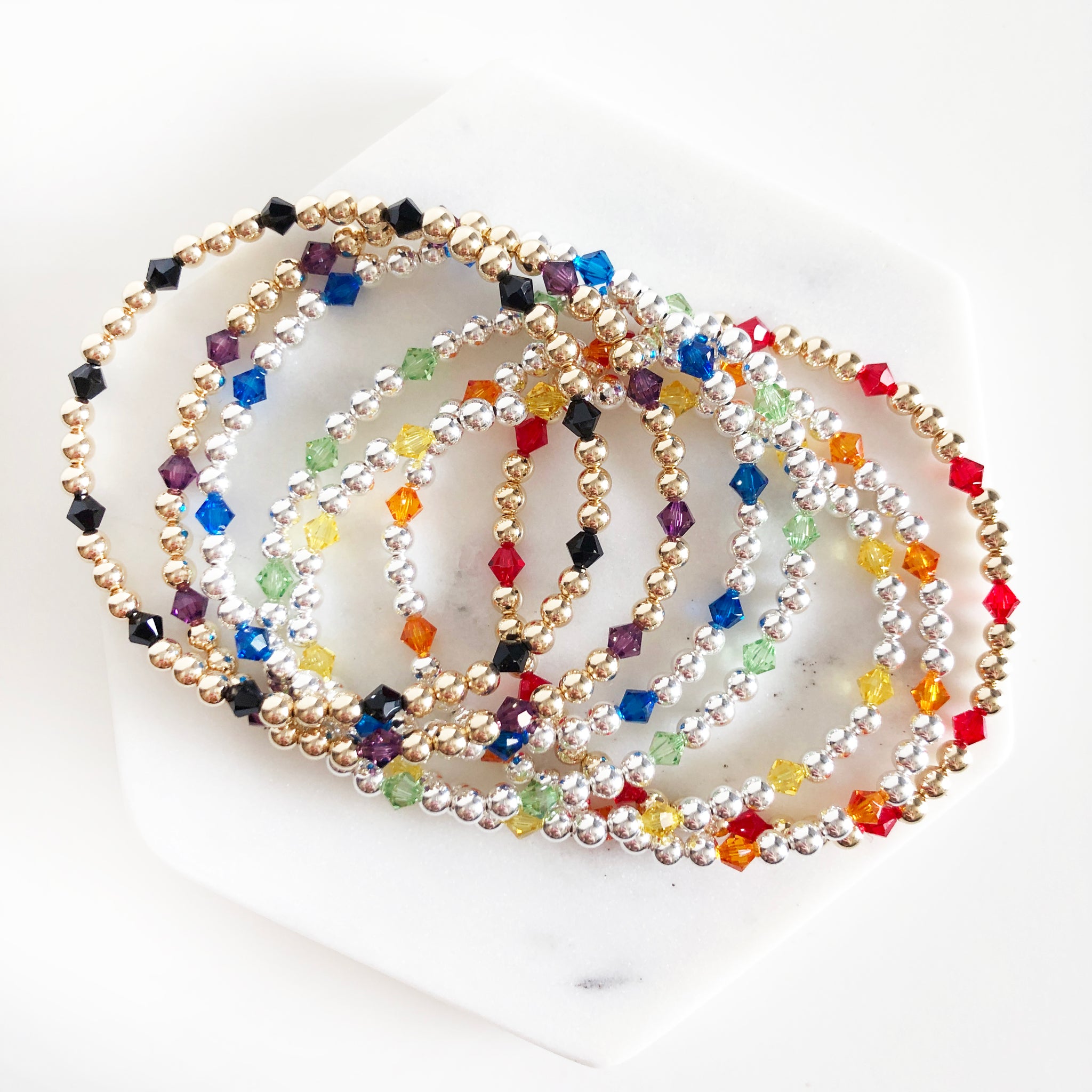 Stack of 14k gold-filled and sterling silver beaded bracelets with Swarovski crystals