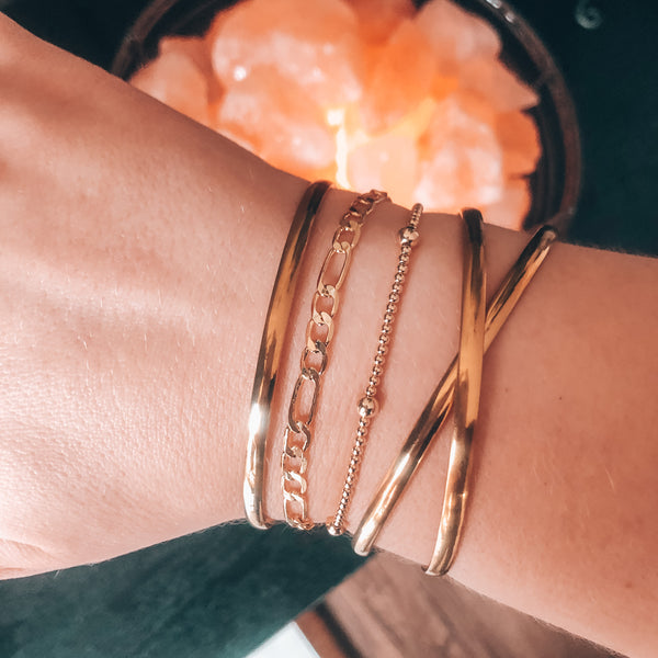 Model photo wearing stack of gold bracelets including x14k gold-filled 2mm beaded bracelet with alternating 4mm beads
