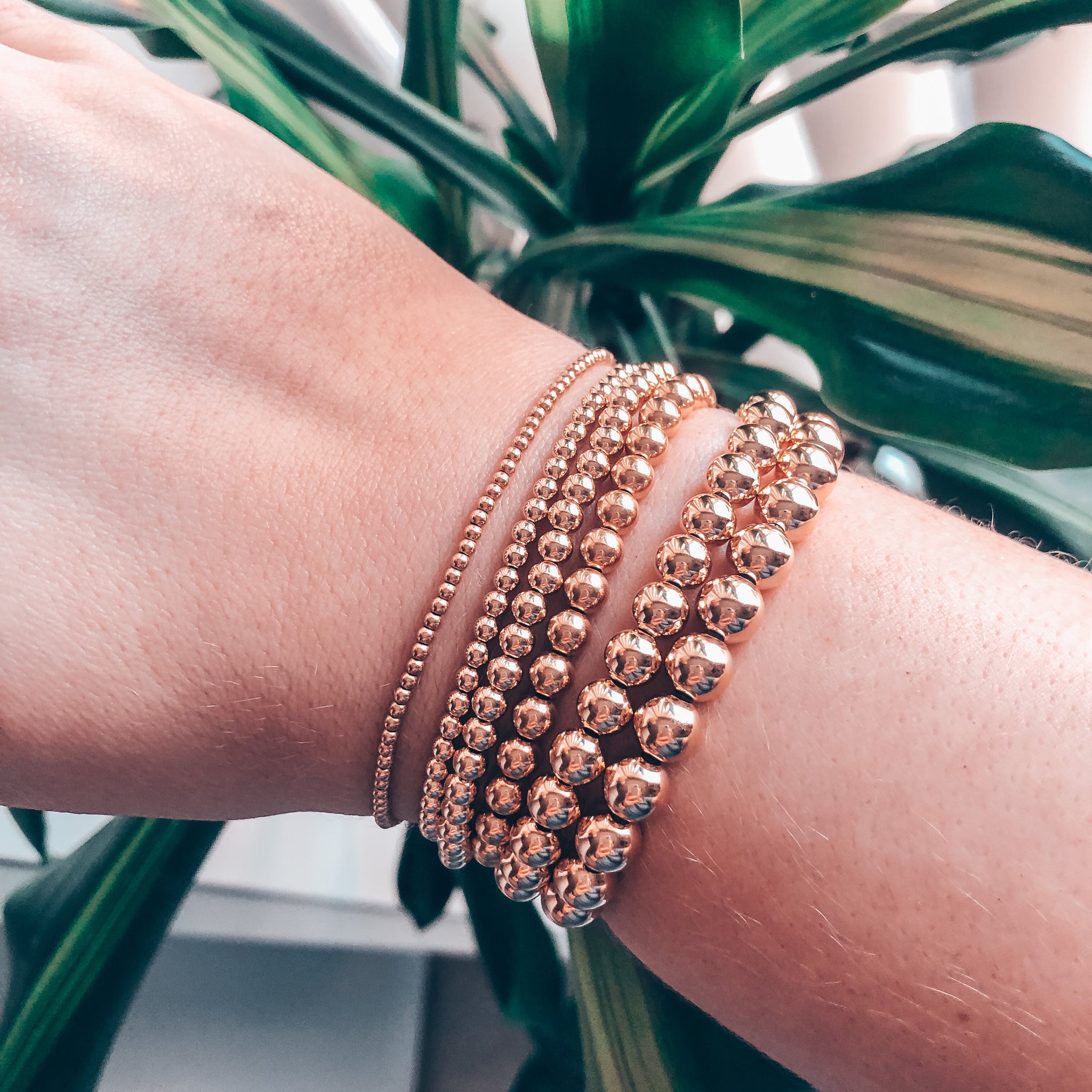 Model photo wearing 14K gold-filled beaded bracelet stack of 6 in all sizes