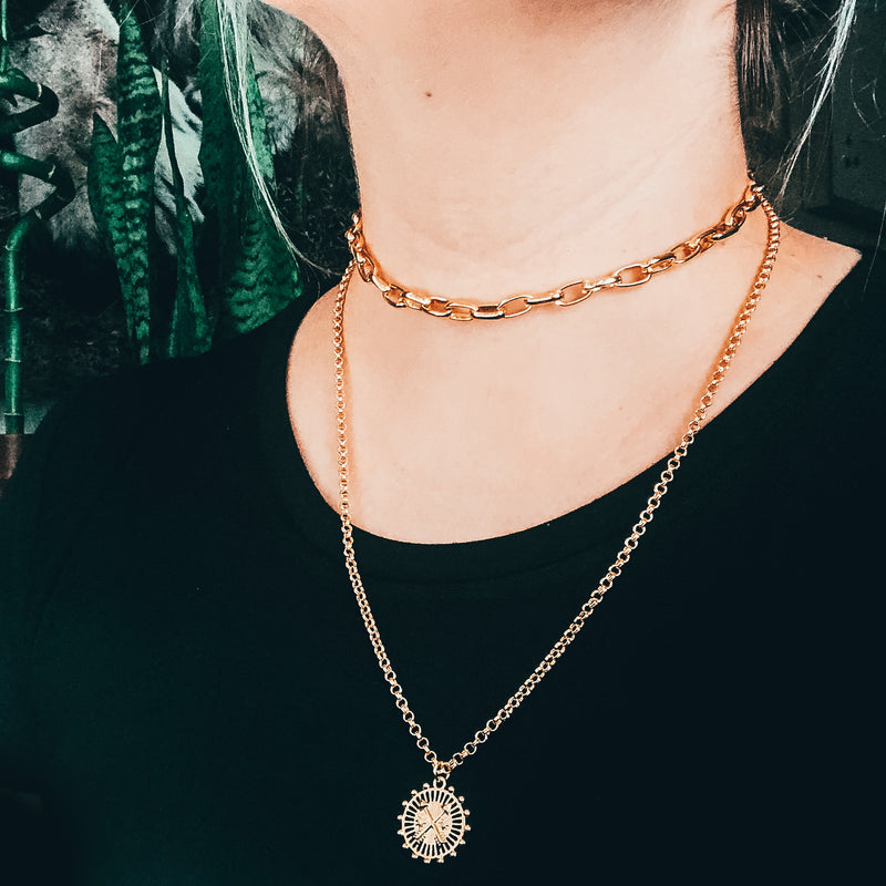 Model photo wearing layered gold necklaces including 14k gold-filled thick chain link choker necklace