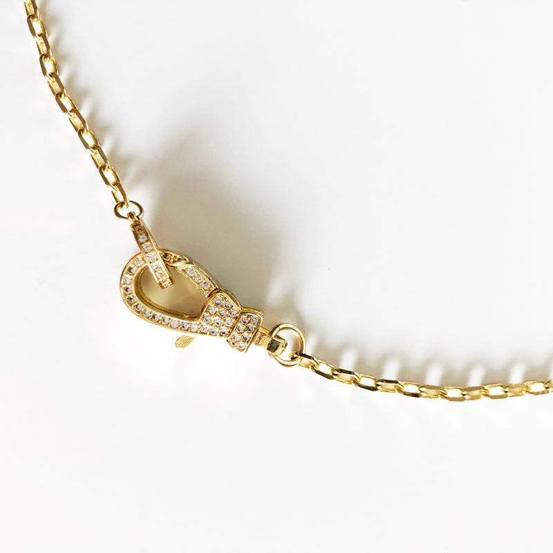 Up close detail view of 14k gold-filled chain necklace with jumbo front closure lobster clasp with CZ accents