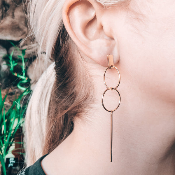 Model photo wearing 14k gold-filled minimal cocktail elegant earrings with a double hoop and stick drop