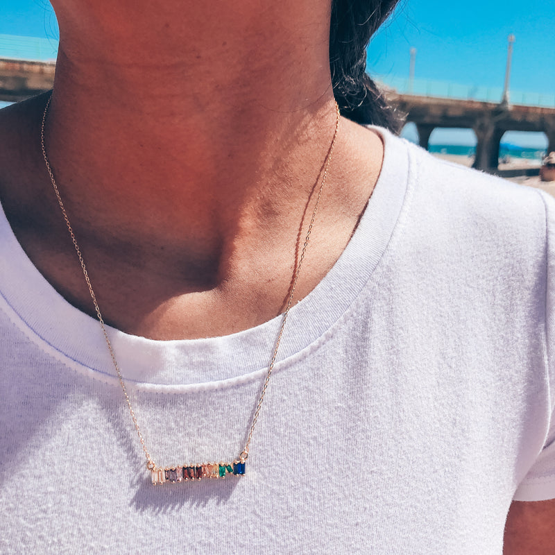 Model photo wearing 14k gold-filled chain necklace with rainbow spectrum CZ bar charm