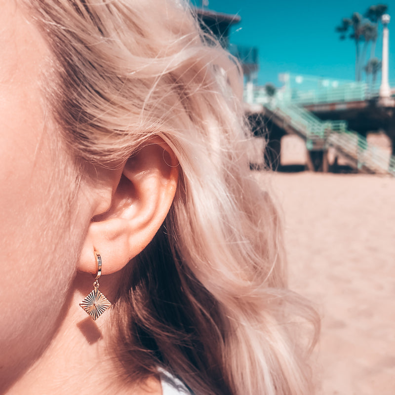 Model photo wearing 14k gold-filled vortex sparkling charm huggie earrings